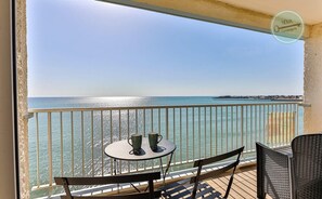Un balcon avec une table et des chaises, offrant une vue dégagée sur la mer.