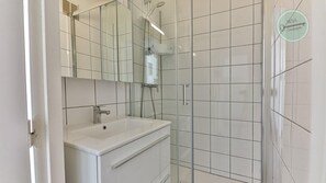 Une salle de bain moderne avec un lavabo blanc, un miroir et une cabine de douche.