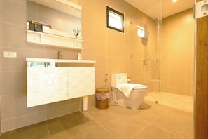 A modern bathroom with a white vanity, a glass shower enclosure, and a toilet.