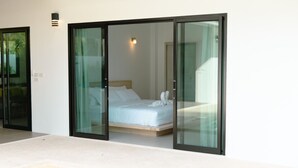 A bedroom with a bed, a glass door, and a small light fixture. - Samui Paradise Pool Villa by Sea N' Rent (Koh Samui)