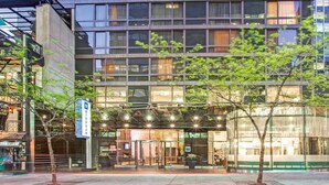 A modern hotel with a glass facade, a covered entrance, and a sign indicating it is a Wyndham property.