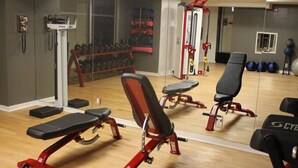 A gym with exercise equipment, a bench, and a wall-mounted dumbbell rack.