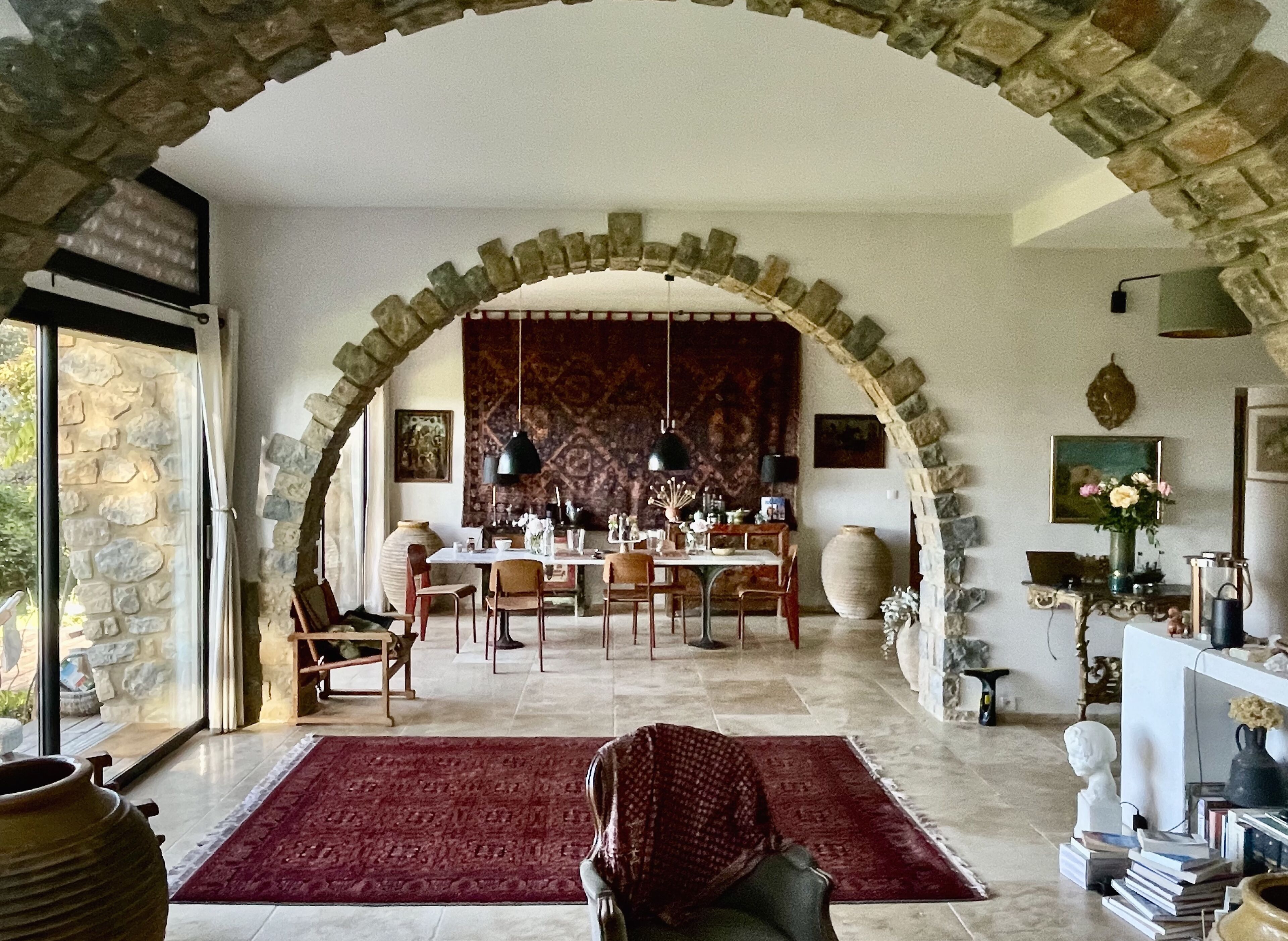 A dining area with a stone archway, a red rug, and a table set for dining.