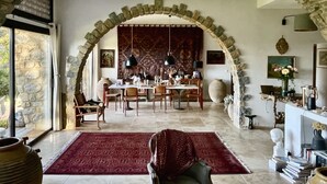 A dining area with a stone archway, a red rug, and a table set for dining. - Exceptional, charming home in coastal Provence, 5 minutes from the beaches (Sanary Sur Mer)