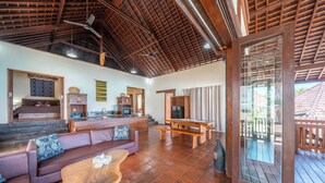 A spacious living area with a wooden ceiling, a sofa set, a dining table, and a kitchen area. - Villa Cemara  (Ceningan Island)