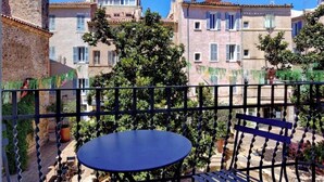Ein Balkon mit Tisch und Stühlen mit Blick auf einen Innenhof mit Gebäuden und Bäumen.