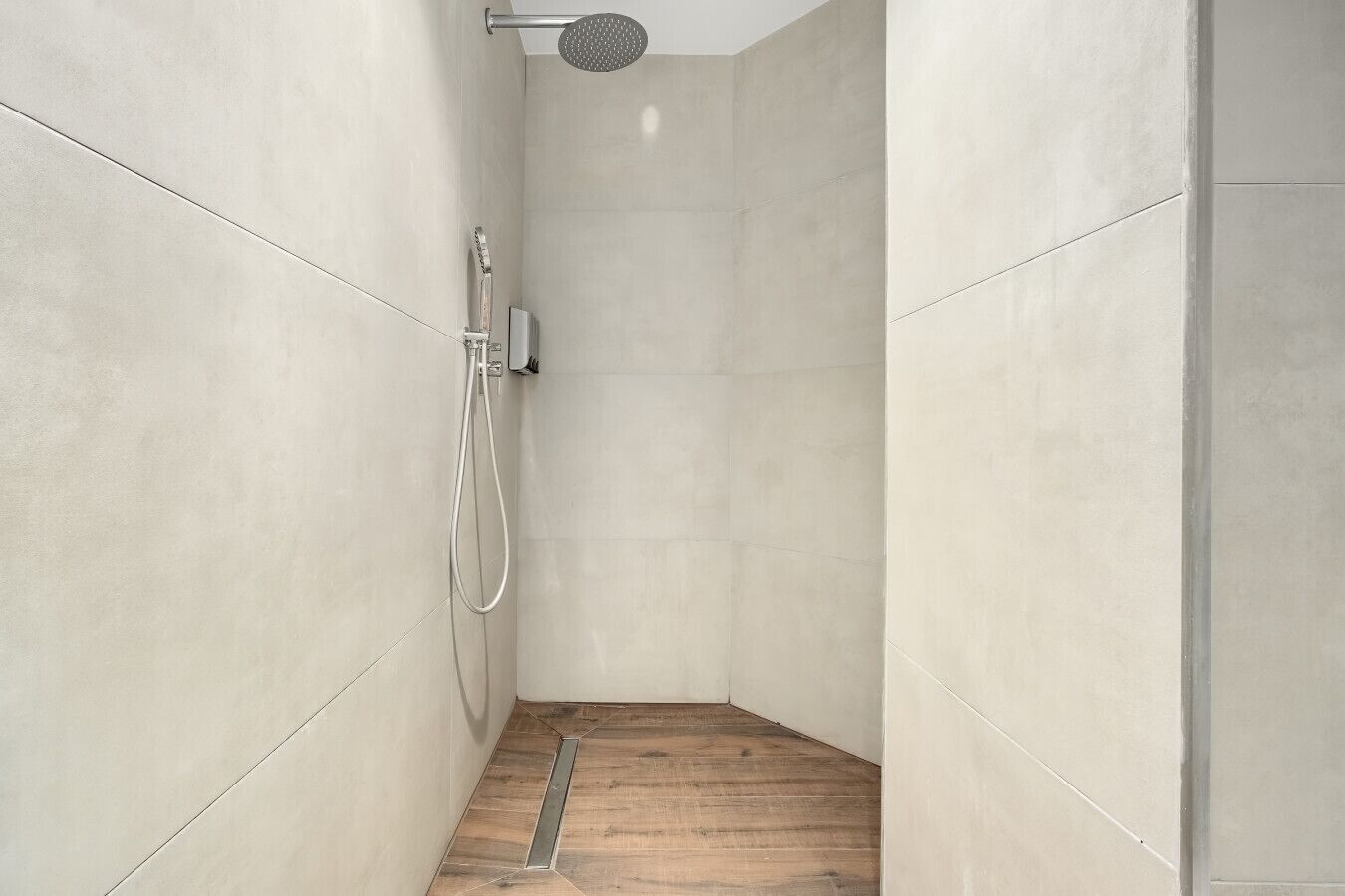 A modern shower with a handheld showerhead and a wall-mounted control panel.