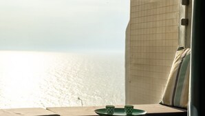 A view from a room with a tiled wall and a window overlooking a body of water. There is a small table with two cups and a plate. - Netanya Beach Pool Studio by Sea N' Rent (Netanya)