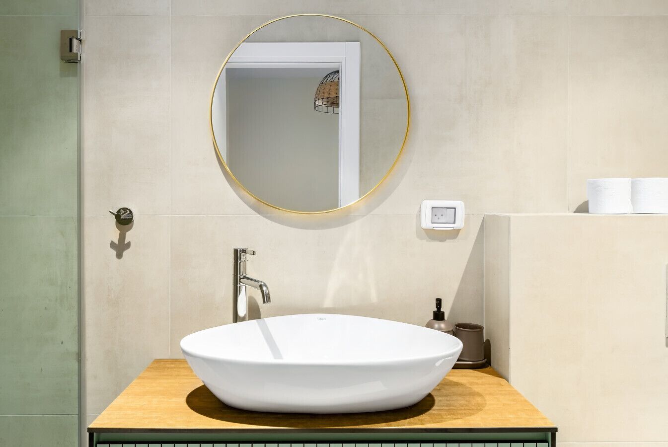 Une salle de bain avec un lavabo sur colonne blanc, un miroir à cadre doré et un meuble-lavabo en bois.