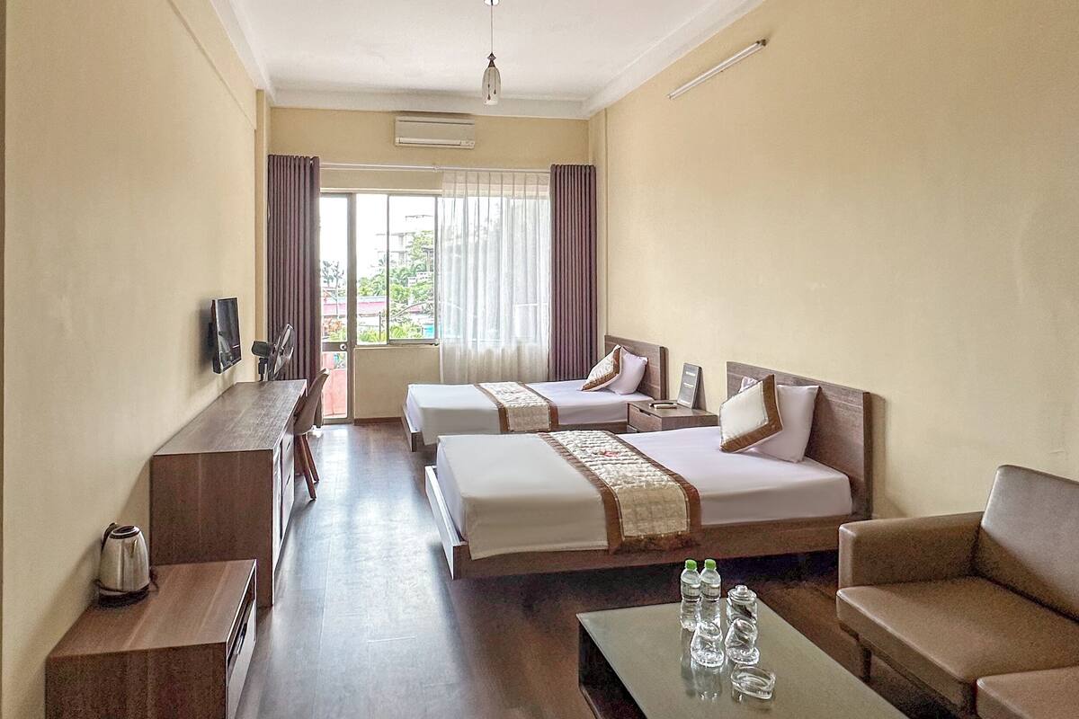 Une chambre d’hôtel avec deux lits, un canapé, une table basse et un téléviseur.