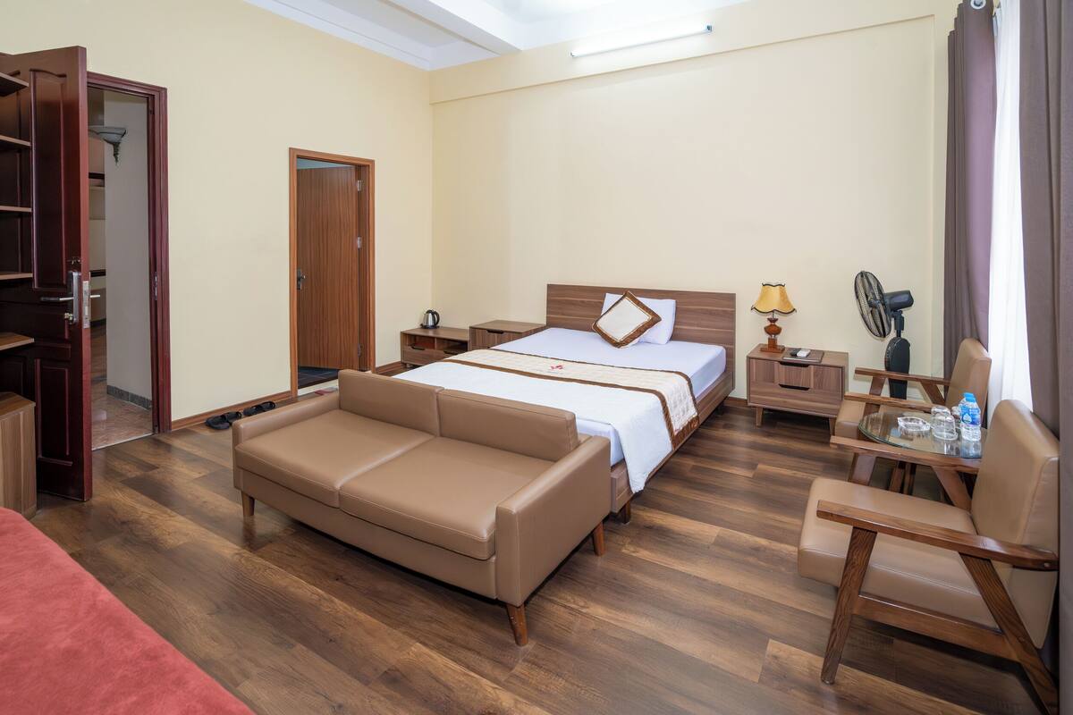 Une chambre d’hôtel comprenant un lit, un canapé, un bureau avec une chaise, une armoire et un miroir.