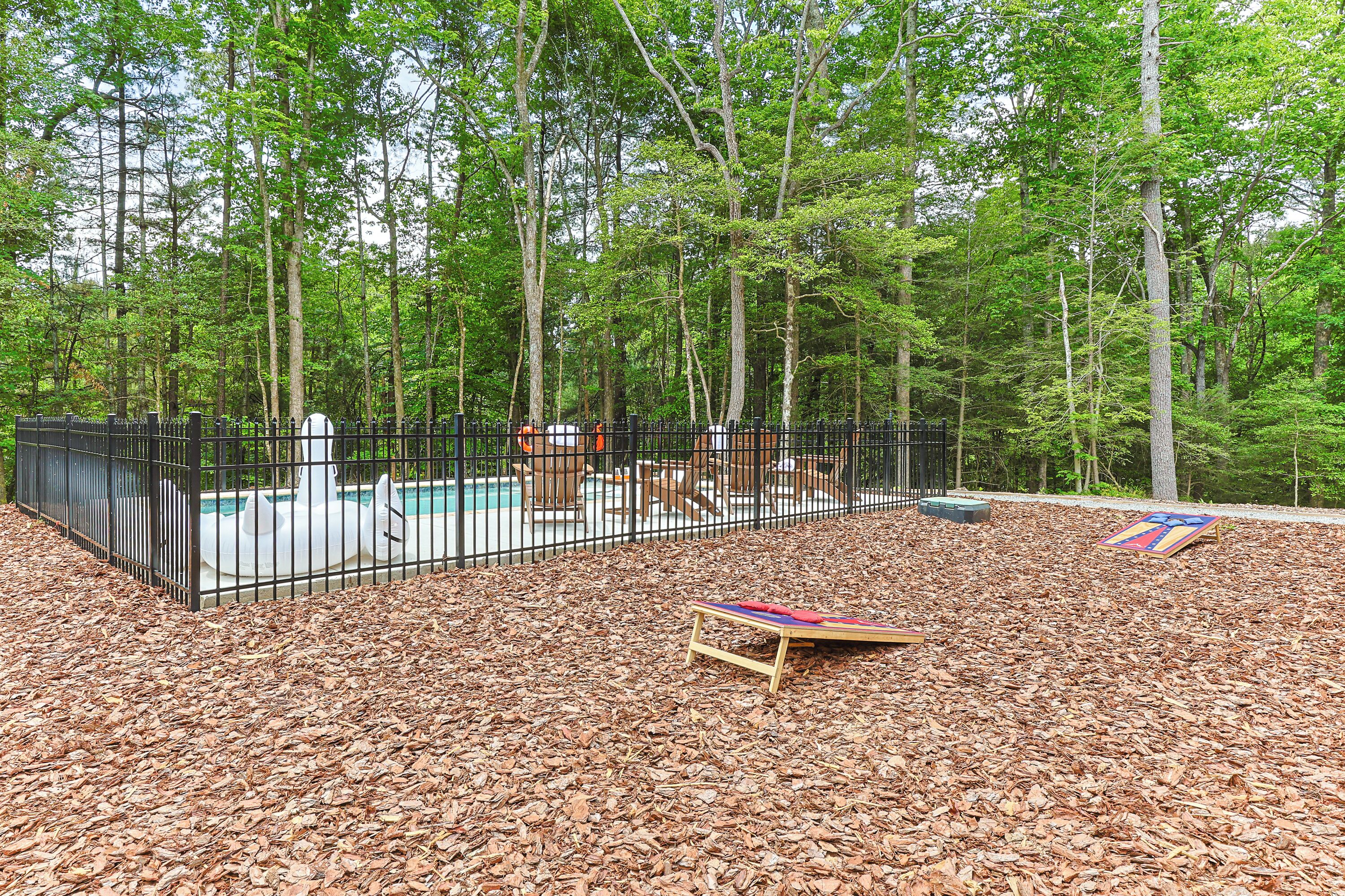 A fenced outdoor area with a pool, surrounded by trees.