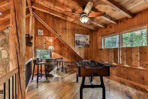 A wooden interior with a foosball table, stone wall, and a bear climbing the wall. - River Time | Ellijay, GA (Ellijay)