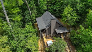 A house surrounded by dense forest, with a visible deck and a hot tub. - A View Above | Ellijay, GA (Ellijay)