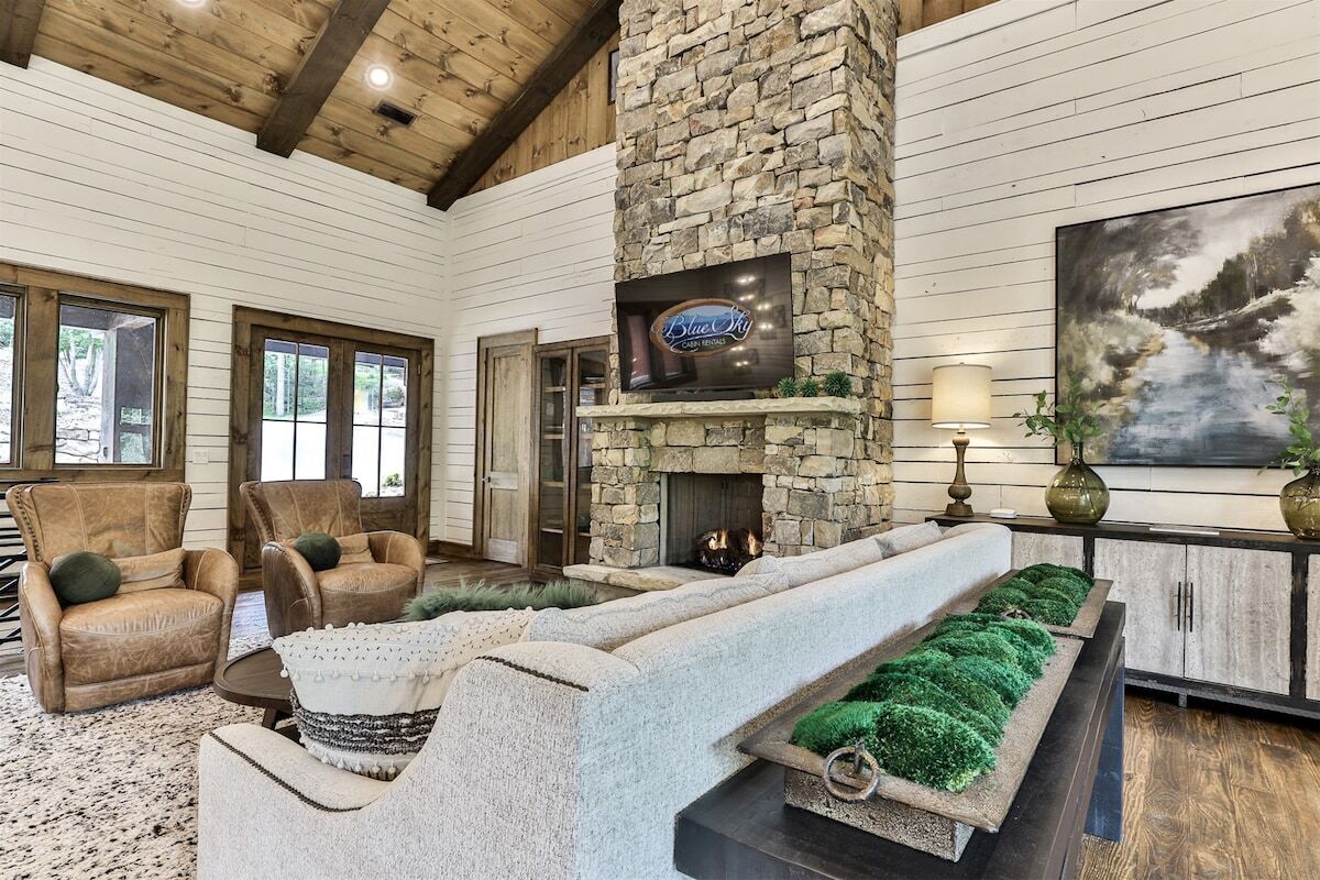A stone fireplace, leather armchairs, a stone bench, and a painting.