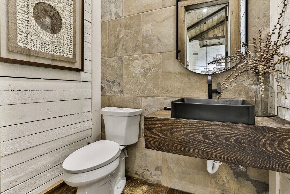 Ein Badezimmer mit Toilette, Holzwaschbecken, Spiegel und einer Wanddekoration.