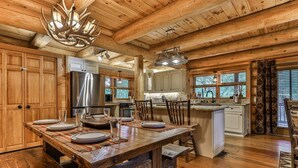 Une cuisine rustique avec des poutres en bois, un grand îlot central et un lustre.