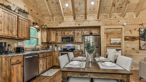 A wooden cabin interior with a kitchen, dining area, and a bed. - Barn Owl`s Bliss | Cherry Log, GA (Ellijay)