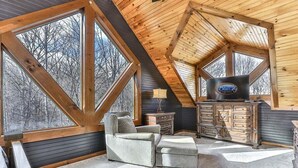 Una habitación acogedora con un ventanal grande, un sofá, un televisor y un armario de madera.