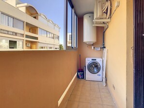 A narrow balcony with a washing machine, a mop, and a bucket. - Le Flamingo (Balaruc-les-Bains)