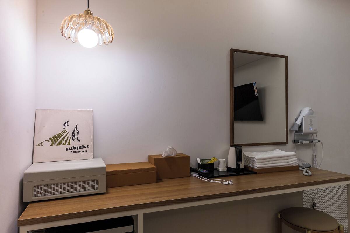 Ein Hotelzimmer mit einem Holztresen, einem Spiegel, einem Fön, einem Telefon und einem gerahmten Bild an der Wand.