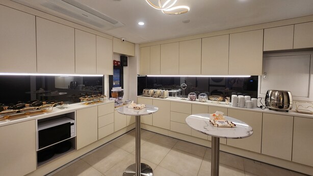 Une cuisine moderne dotée d’appareils électroménagers intégrés, d’un îlot central et de luminaires suspendus.