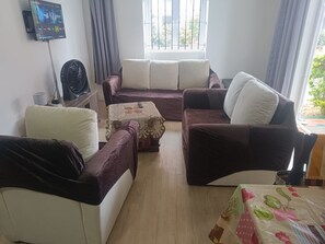 Una sala de estar con un conjunto de sofá, una mesa de centro y un televisor montado en la pared.