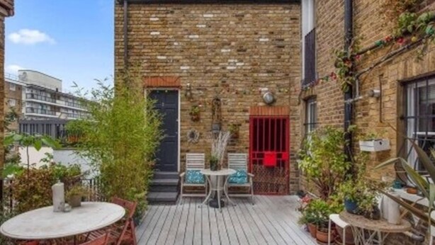 A courtyard with a brick building, a round table, and chairs. - Artist home central london (London)