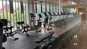 Ett gym med träningsutrustning, stora fönster och ett trägolv.