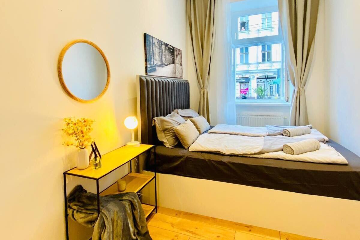 A compact bedroom with a bed, bedside table, and a window with curtains.