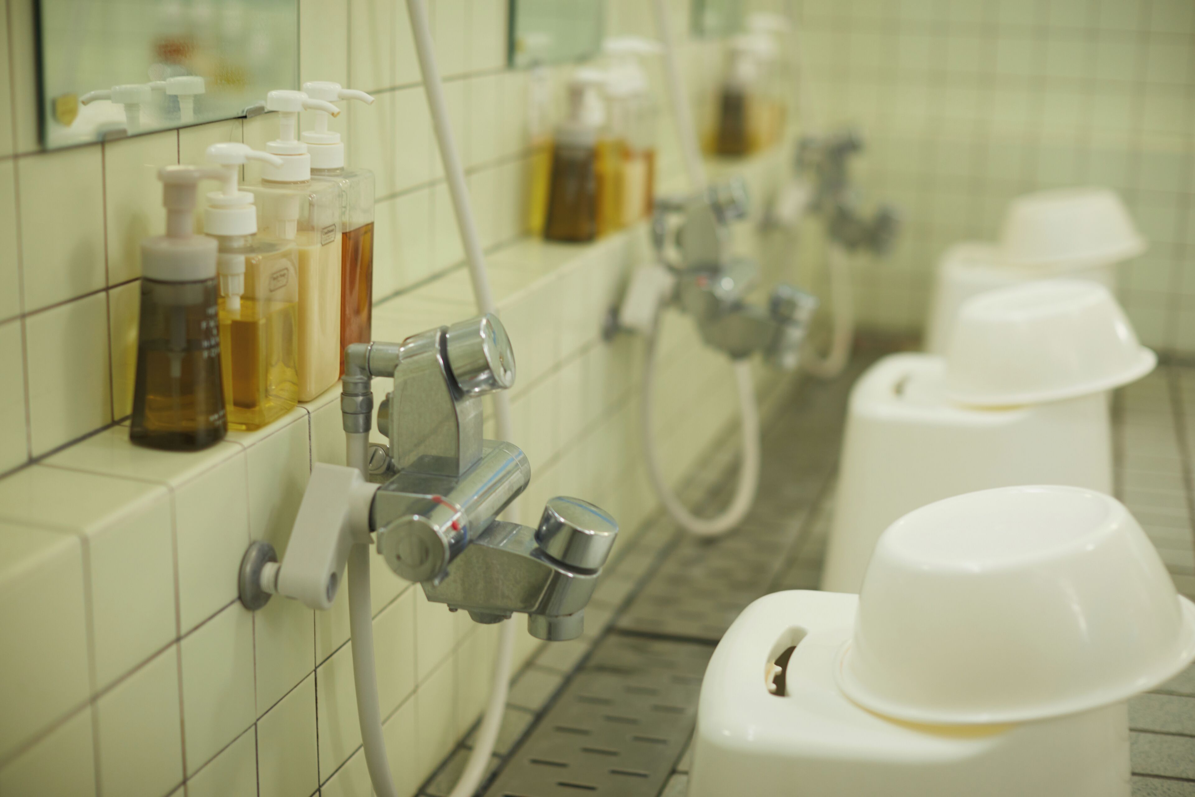 Een badkamer met meerdere wastafels, zeepdispensers en papieren handdoekdispensers.