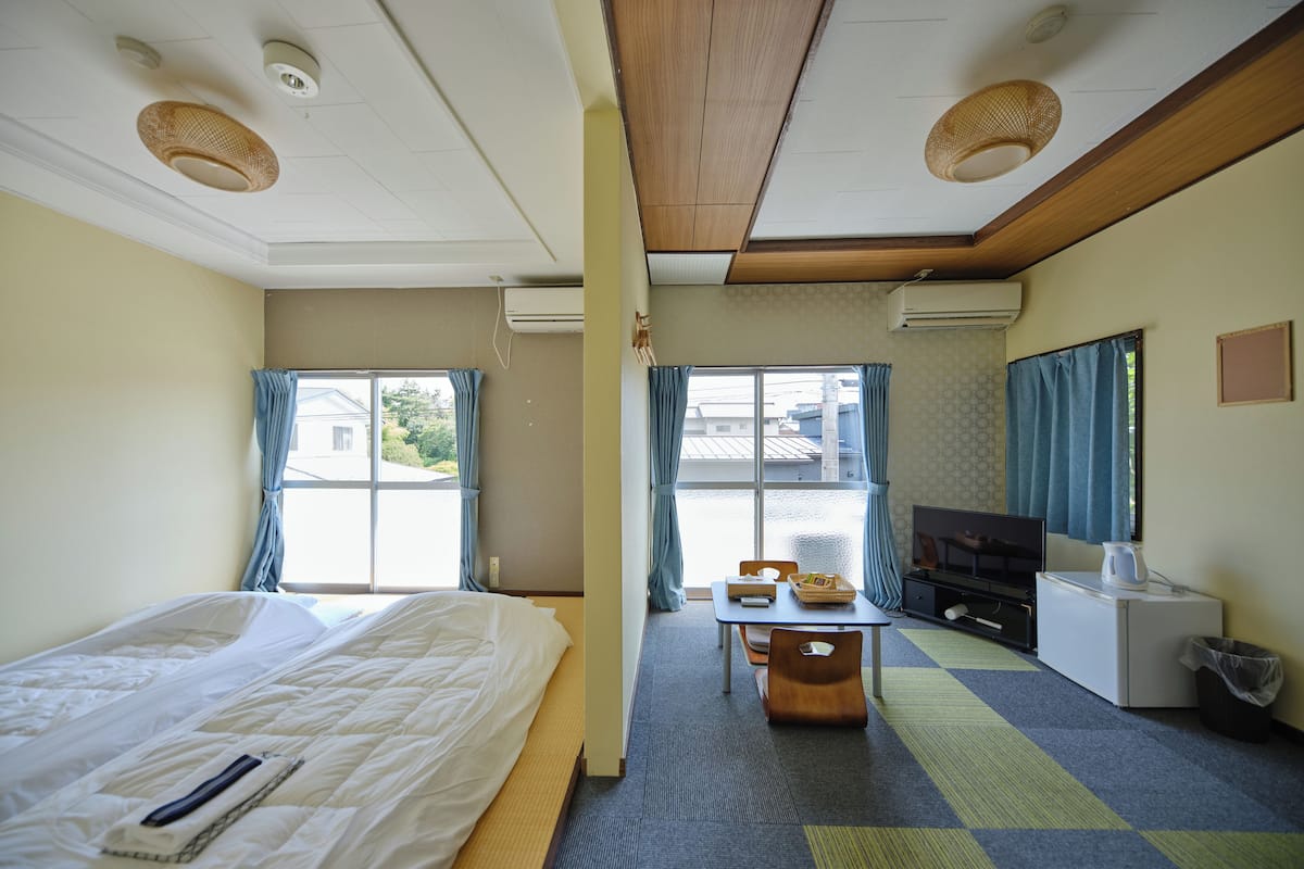 A hotel room with a bed, a desk, a television, and a window with curtains.