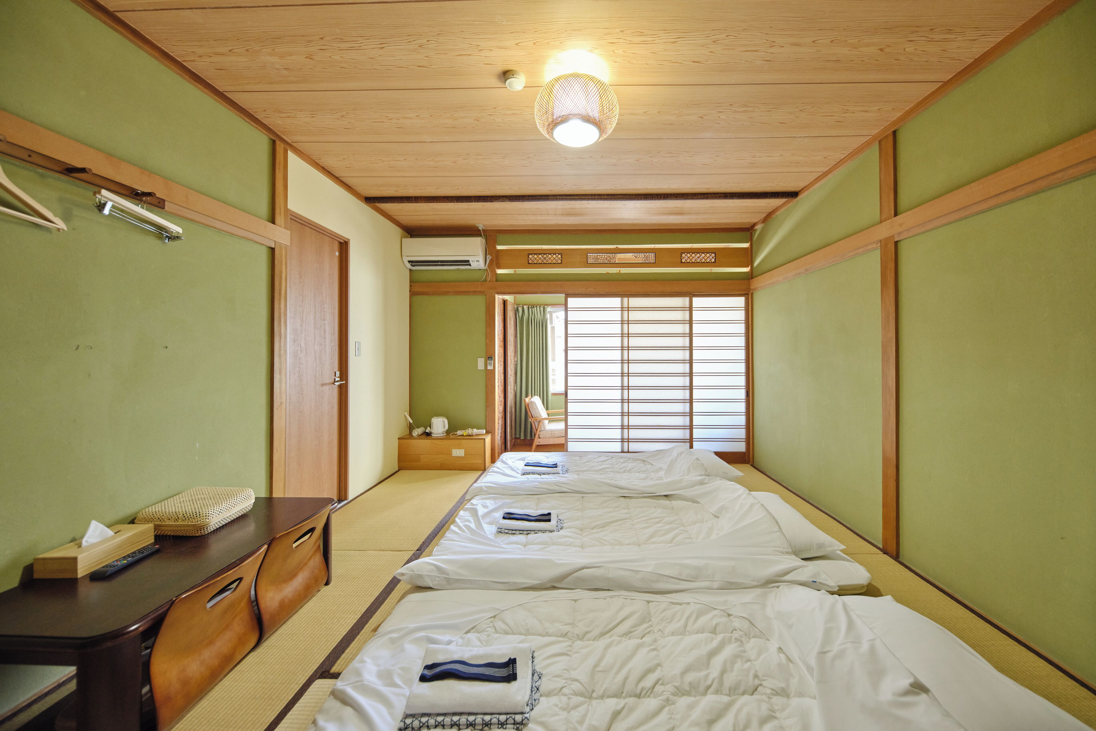 A traditional Japanese-style room with tatami flooring, a wooden ceiling, and shoji screens.