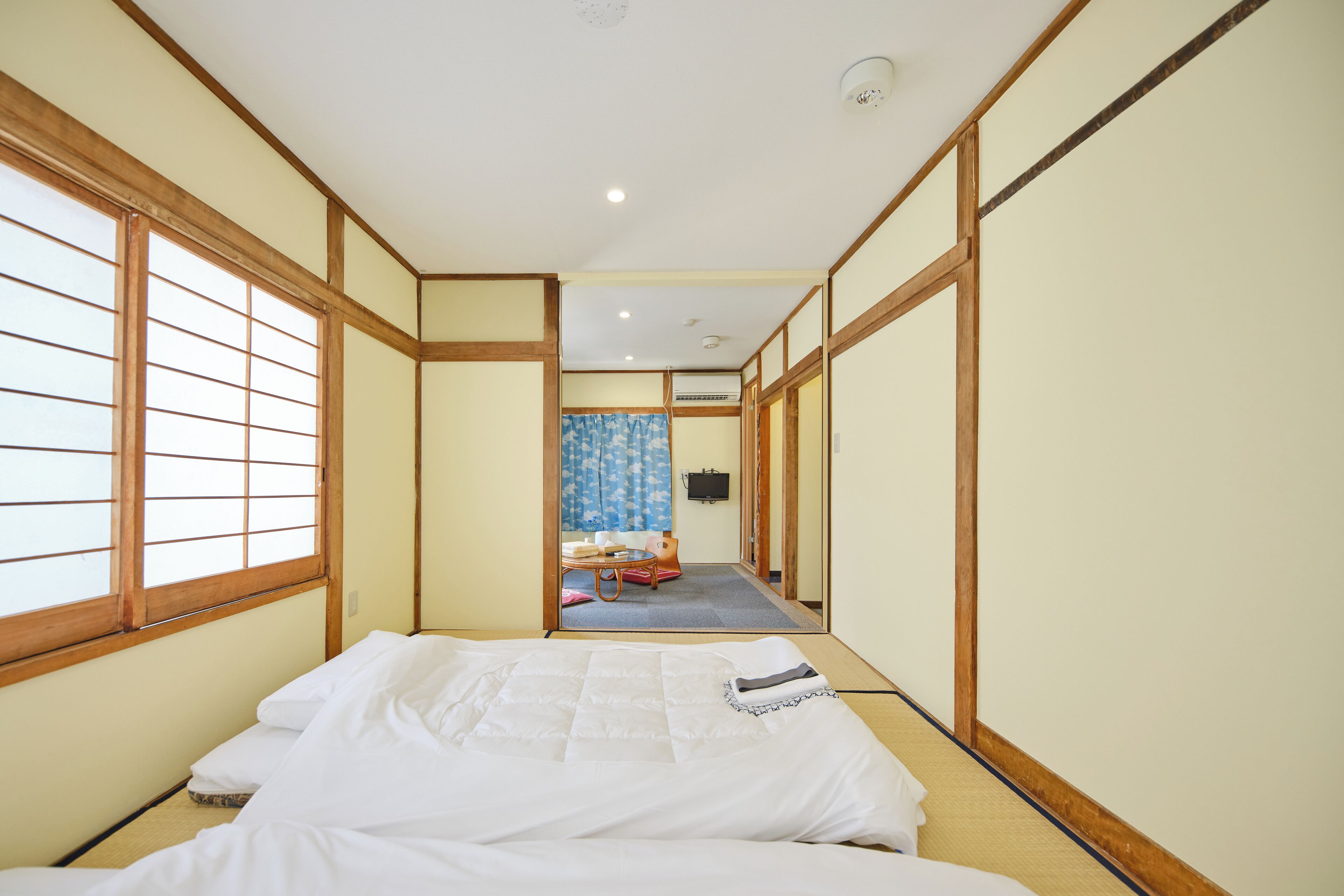 A traditional Japanese-style room with tatami flooring, a low bed, and sliding doors leading to a bathroom.