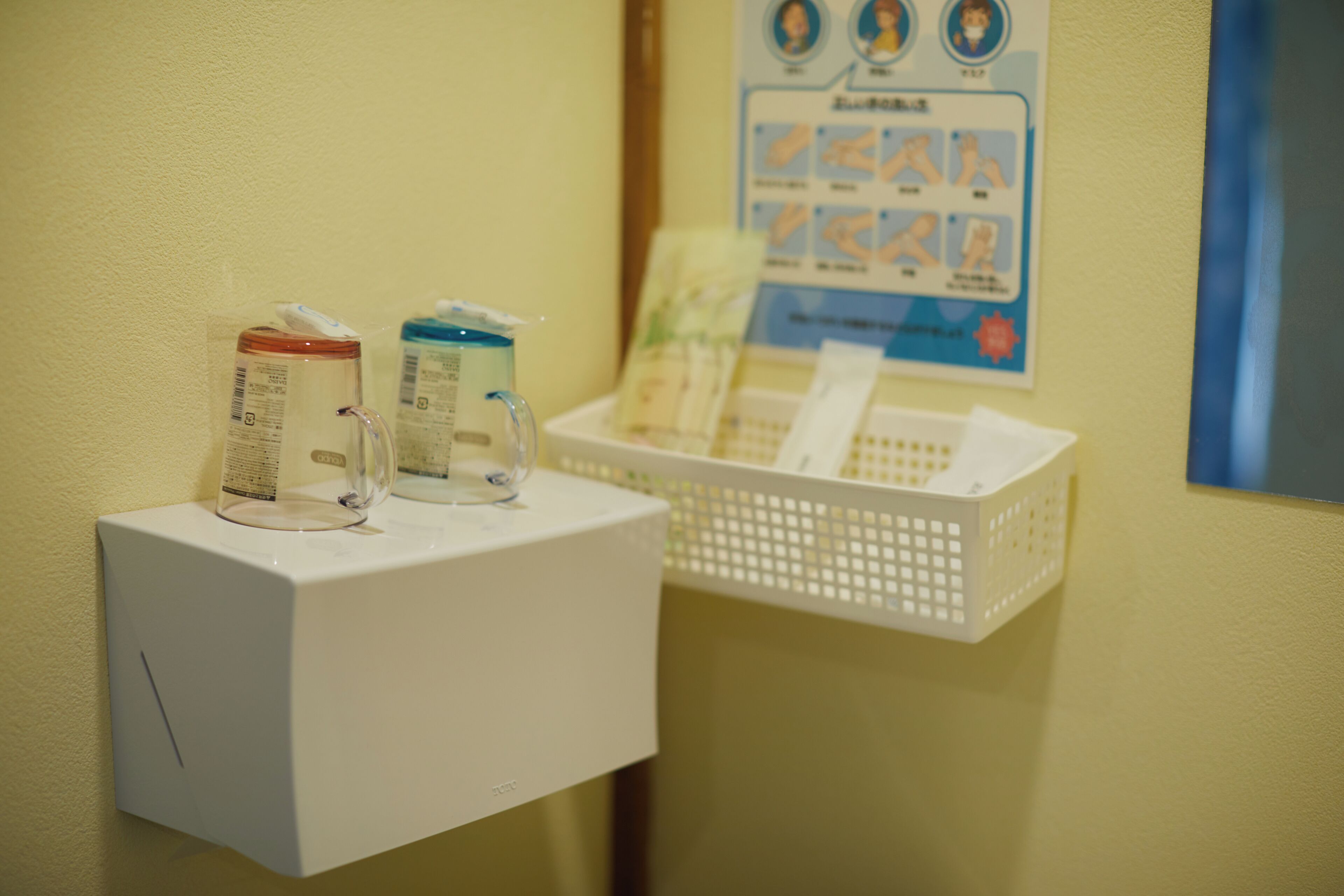 A small white cabinet with a tissue dispenser and a glass container on top.