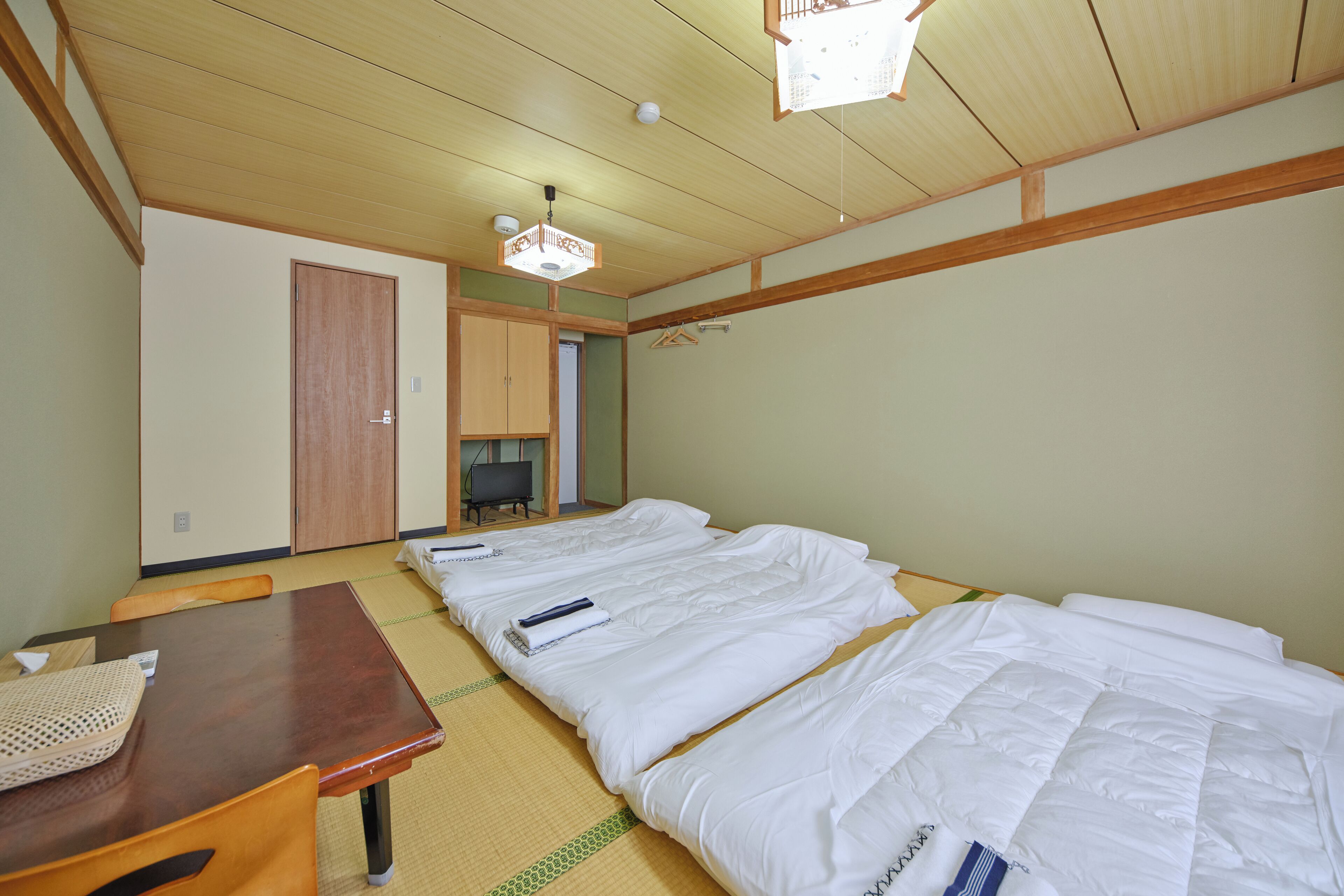 A traditional Japanese room with tatami flooring, a wooden table, and a futon bed.