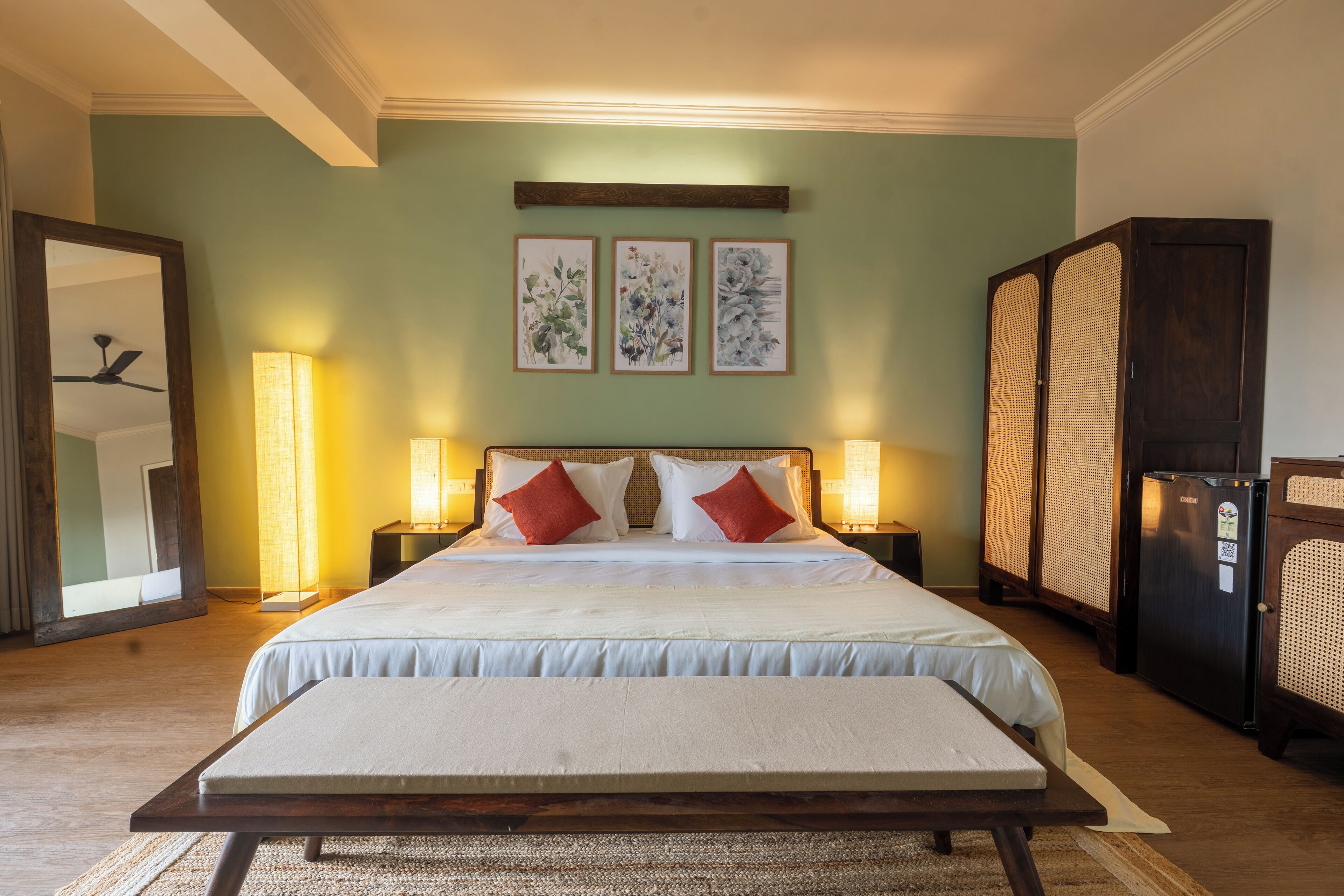 A hotel room with a large bed, two bedside lamps, a mirror, and a wardrobe.