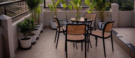 A terrace with potted plants, a round table, and chairs.
