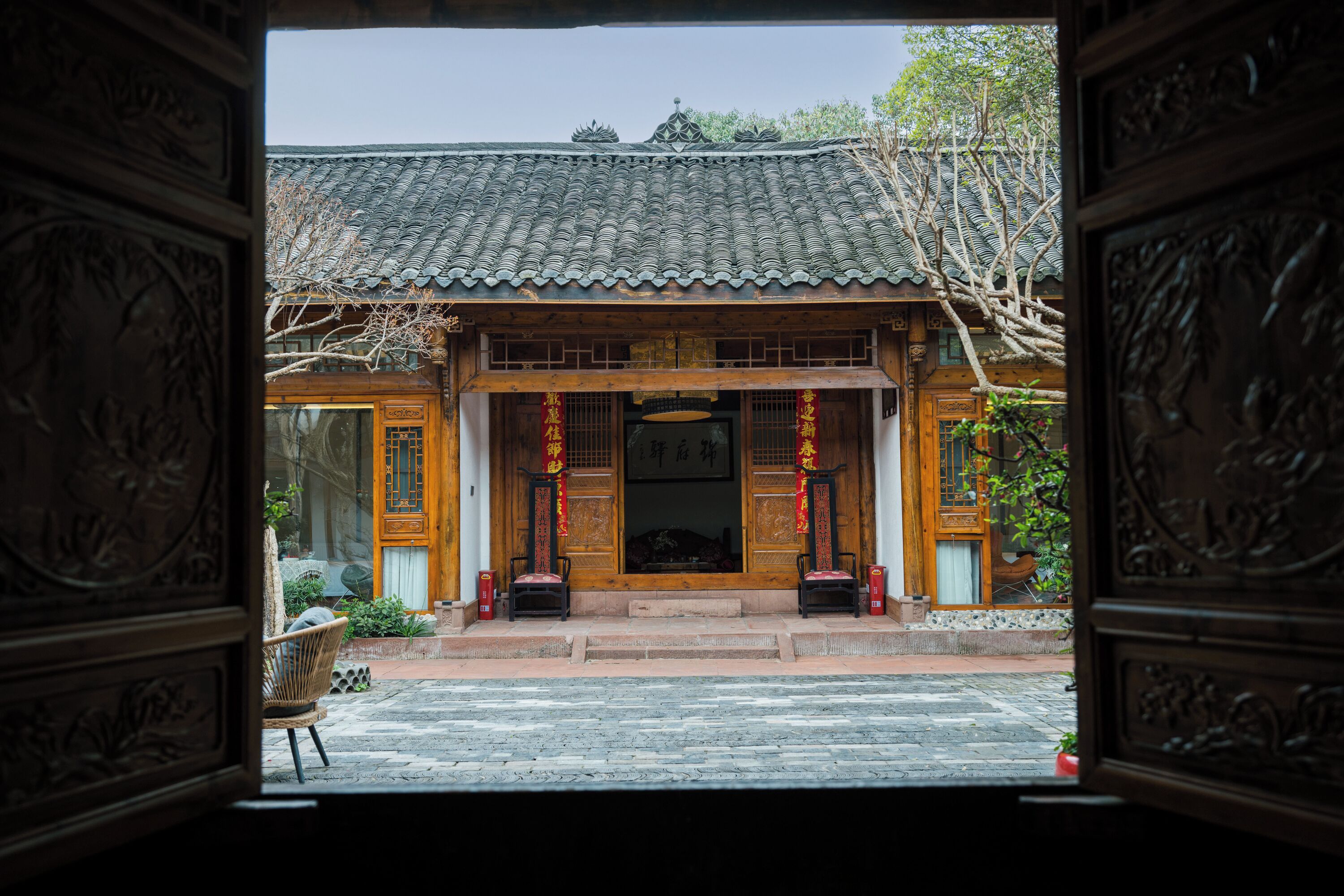 A traditional building with a tiled roof, wooden doors, and a stone-paved entrance.