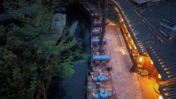 Een restaurant aan de rivier met terras en traditionele architectuur.