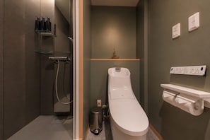 Une salle de bain moderne avec une douche à l’italienne, des toilettes et une petite étagère contenant des articles de toilette.