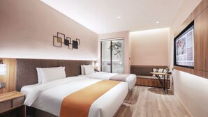 Ein Hotelzimmer mit zwei Betten, einem kleinen Tisch, einem Fernseher und einer Schiebetür zu einem Balkon.