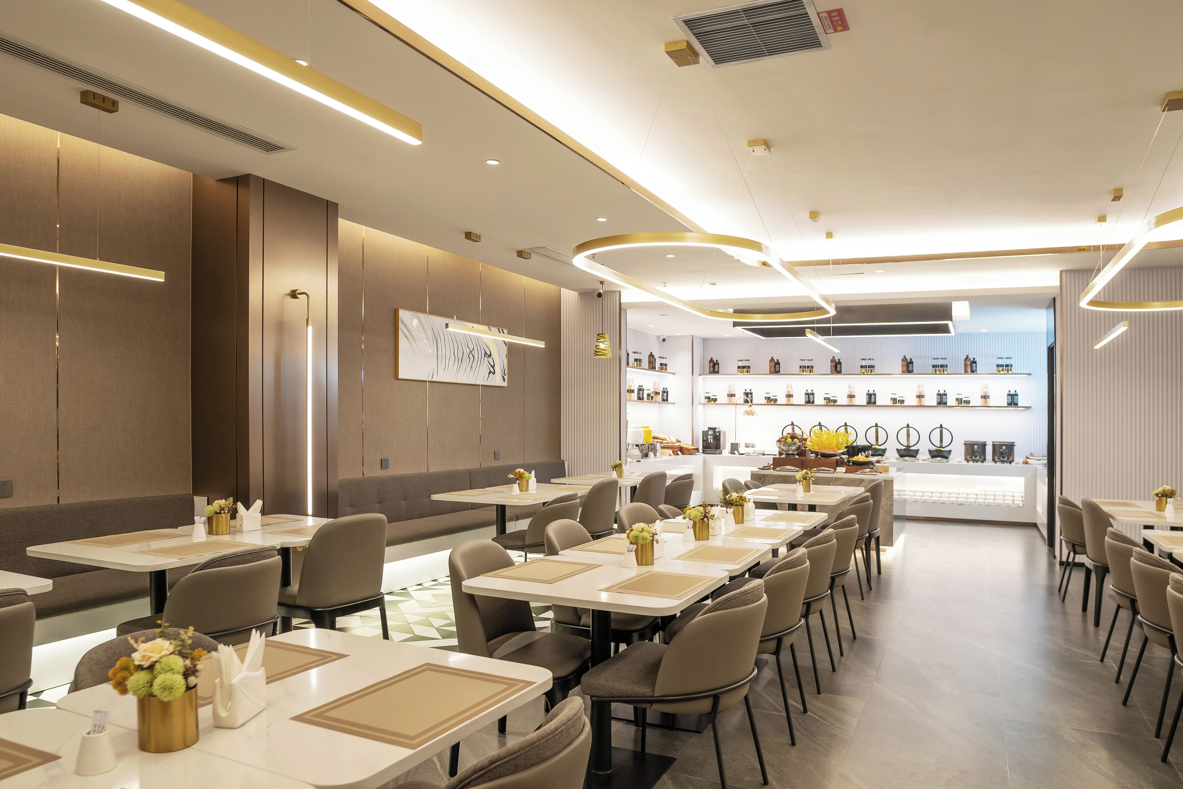 Um restaurante moderno com mesas compridas, cadeiras e um bar ao fundo.