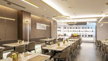 Um restaurante moderno com mesas compridas, cadeiras e um bar ao fundo.
