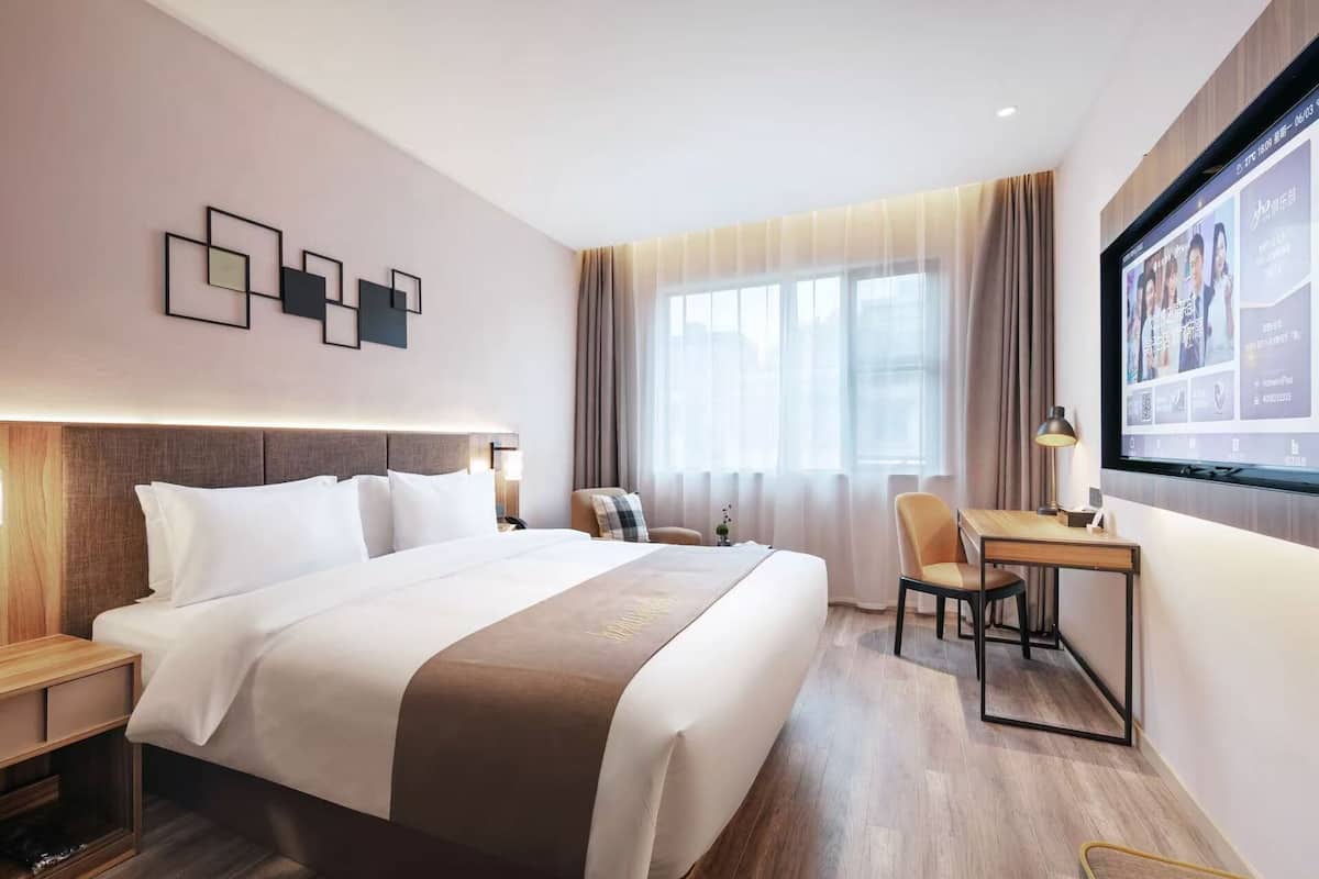 A hotel room with a large bed, a desk, and a television.