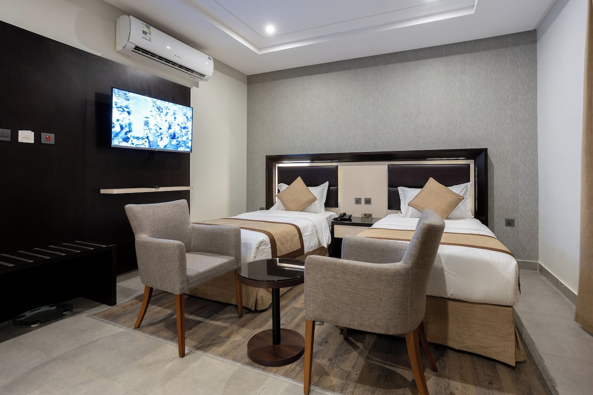 A hotel room with a large bed, two bedside tables, a TV, and two armchairs.
