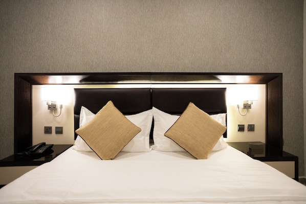 A neatly made bed with two pillows, a bedside phone, and two wall-mounted lamps. - Hotel SDU Boutique Al Madinah (Madinah)