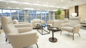 A modern hotel lobby with a spacious layout, featuring multiple seating areas, a glass coffee table, and a view of the city through large windows. - Hotel SDU Boutique Al Madinah (Madinah)