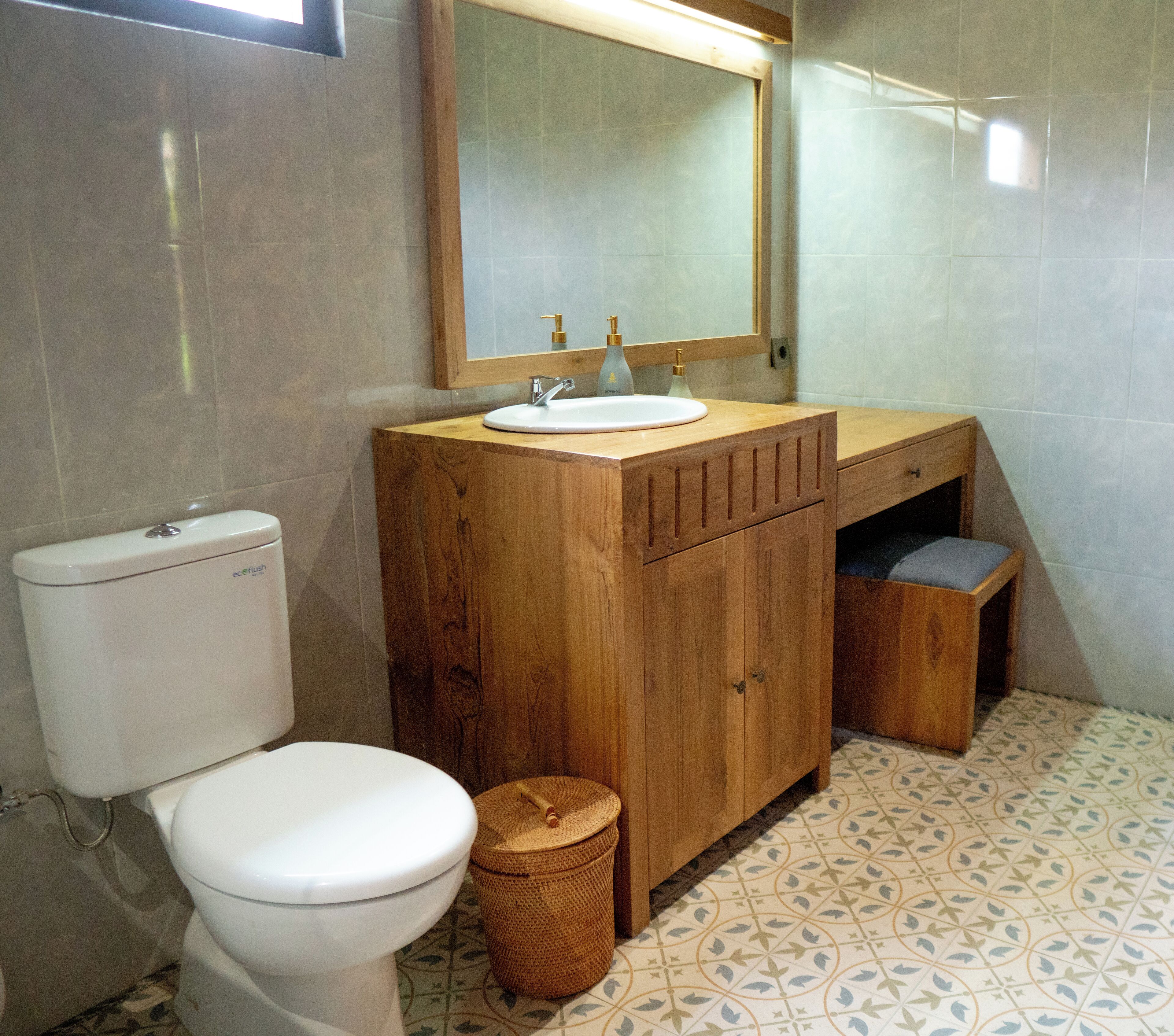 Een badkamer met toilet, een houten wastafelmeubel met een wastafel en een spiegel.