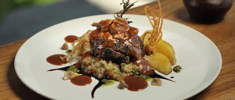 Ein Teller Essen auf einem Holztisch vor unscharfem Grün.